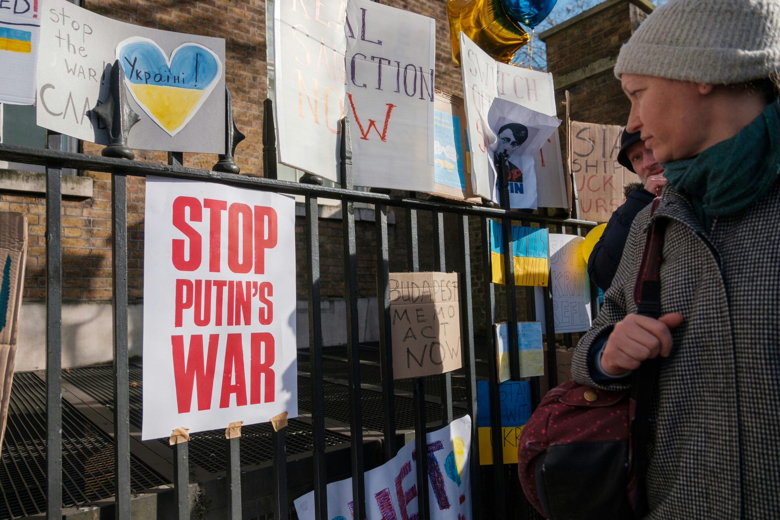 a woman standing in front of a fence with signs on it