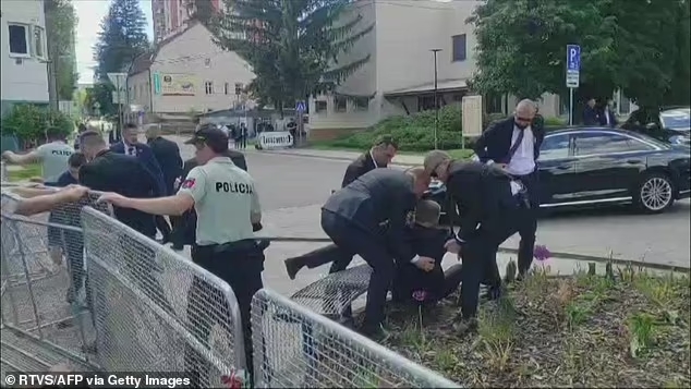 Le Premier ministre slovaque Robert Fico, au centre, s'entretient avec des gens avant la séance à l'extérieur du cabinet dans la ville de Handlova, en Slovaquie, quelques instants avant la fusillad