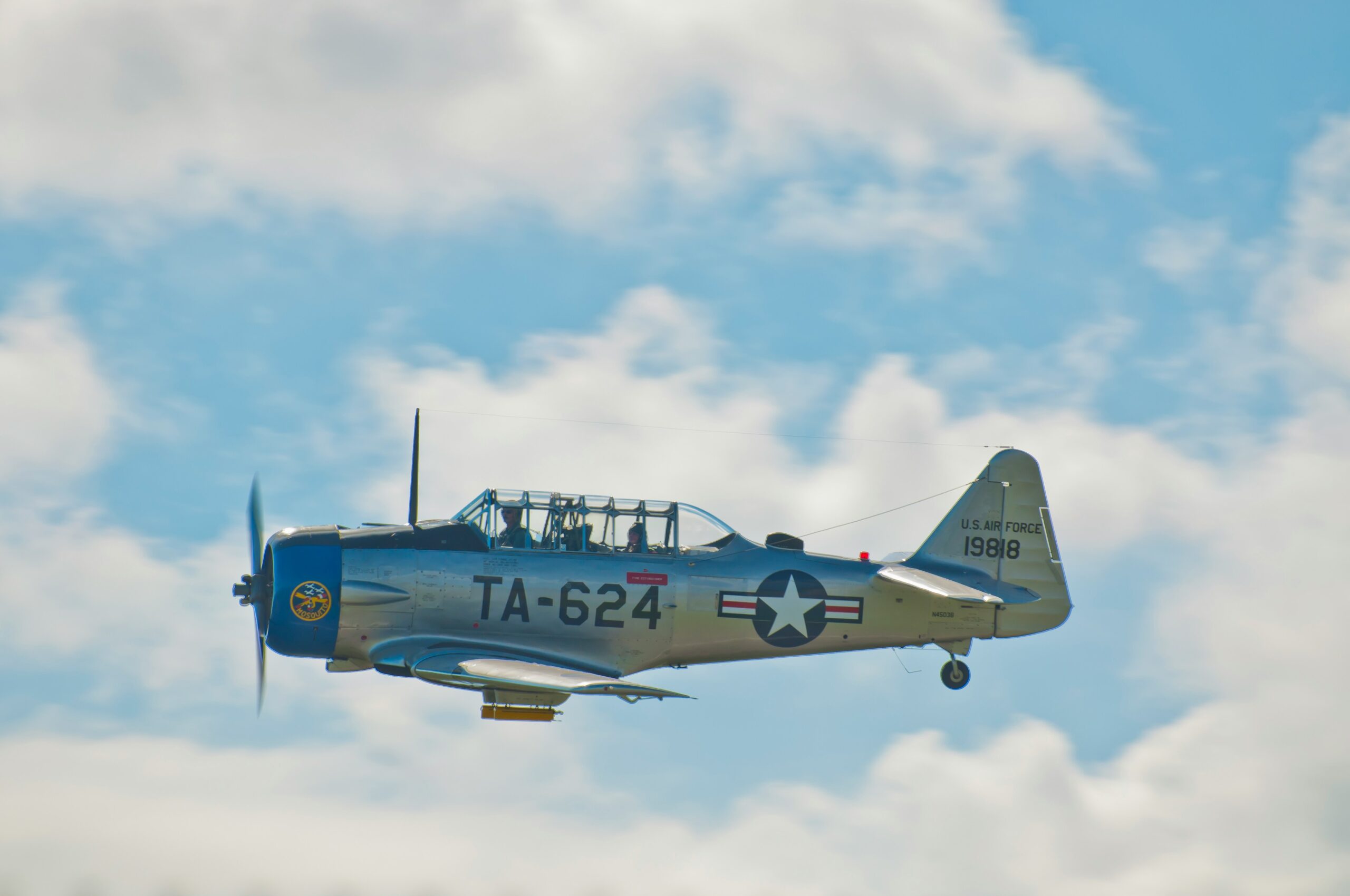 a small airplane flying through a cloudy blue sky