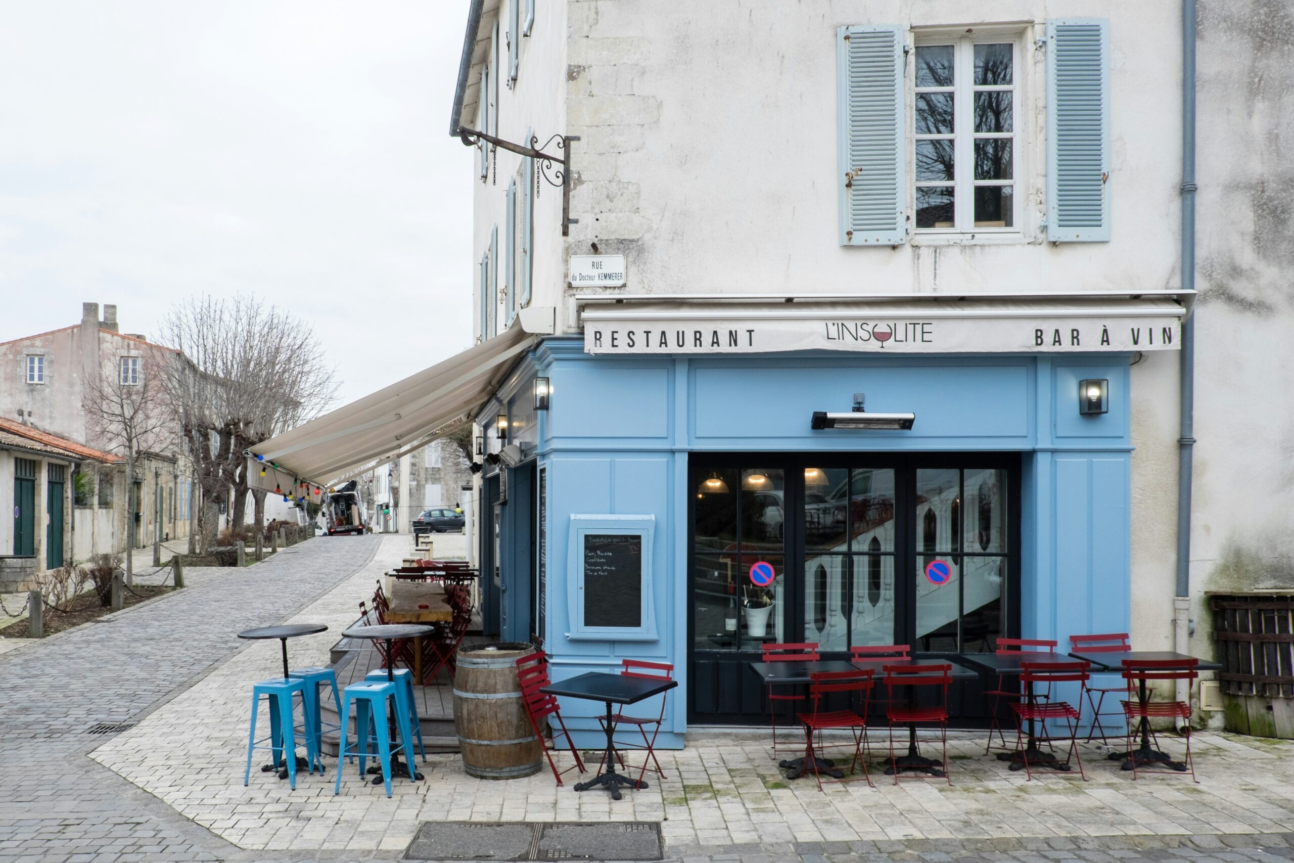 white concrete building with blue plastic chairs and tables