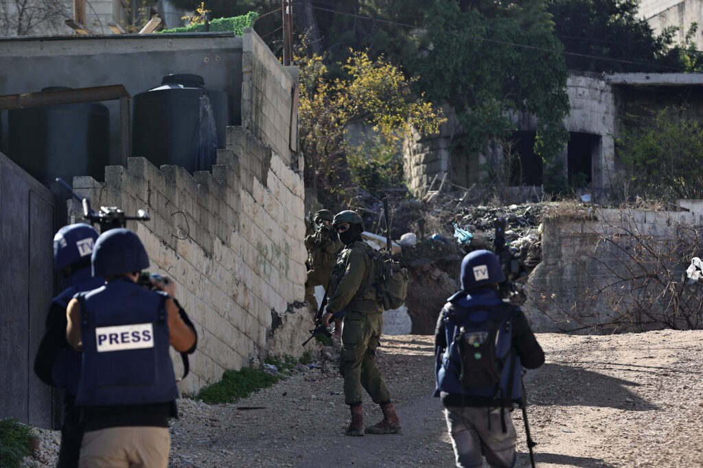 29 novembre 2023. Un soldat israélien vise derrière un mur alors que des journalistes couvrent leur patrouille dans le camp de réfugiés de Jénine, en Cisjordanie occupée.
Zain JAAFAR/AFP