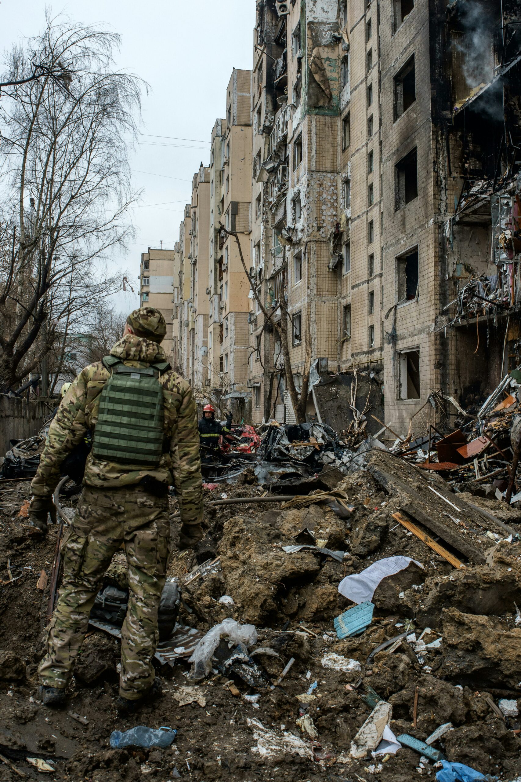 a man in camouflage walking through a destroyed building